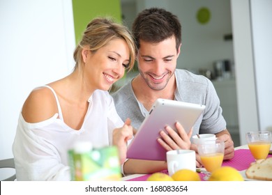 Couple Reading News On Digital Tablet