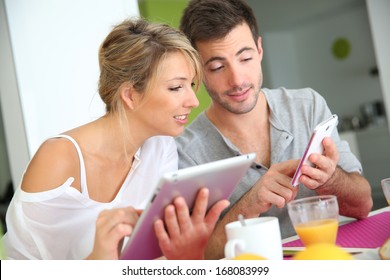 Couple Reading News On Digital Tablet