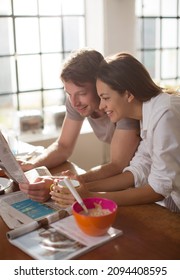 Couple Reading Newspaper Together At Breakfast