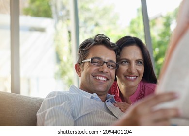 Couple Reading Newspaper Together On Sofa