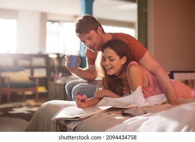 Couple Reading Newspaper Together On Bed