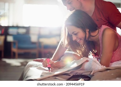 Couple Reading Newspaper Together On Bed