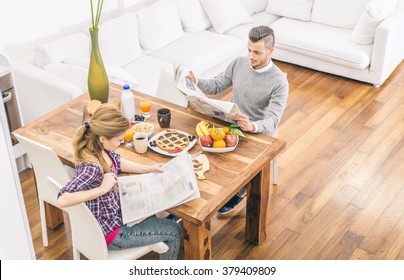 Couple reading newspaper while having breakfast in the morning - Domestic life, family living in a modern house - Powered by Shutterstock