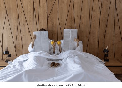 couple reading newspapers in the hotel bed - Powered by Shutterstock