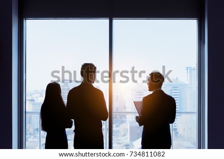 Couple and real estate agent stands near window and speaks before signing contract. Business concept