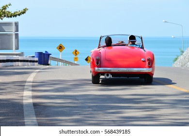 Couple In A Red Car On The Road Beside The Sea