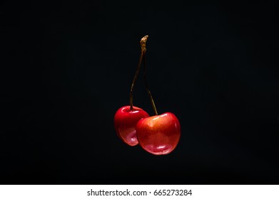 Couple Of Red Cherries On The Black Isolated Background