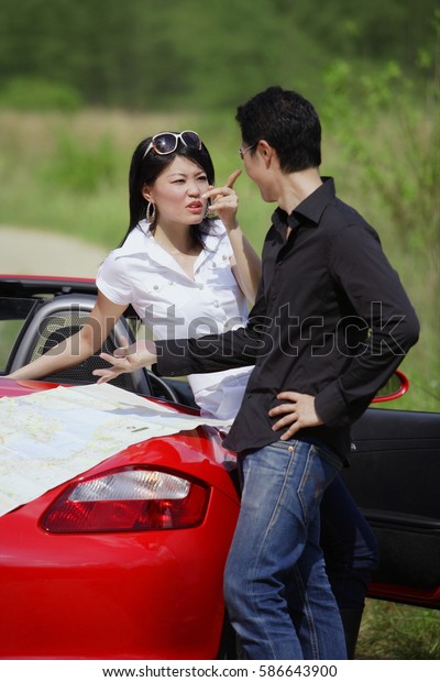 Couple with red sports car,\
arguing