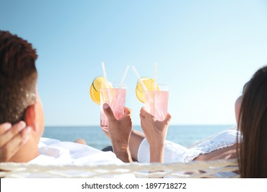 Couple with refreshing cocktails relaxing in hammock on beach - Powered by Shutterstock