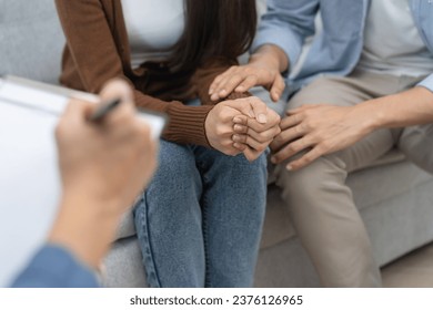 couple relationship therapy with a counselor. Close Up hands of the psychologist take notes on a clipboard during a conversation with clients to find problems and solution. - Powered by Shutterstock