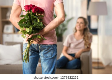 couple, relationships and people concept - happy woman looking at man hiding bunch of roses behind his back - Powered by Shutterstock