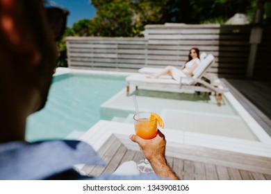 Couple Relax And Drink Cocktail On Beach Resort Hotel New Swimming Pool. POV View.