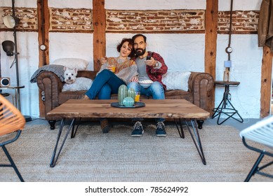 Couple Relaxed At Home In The Couch Watching Tv And Eating Popcorn