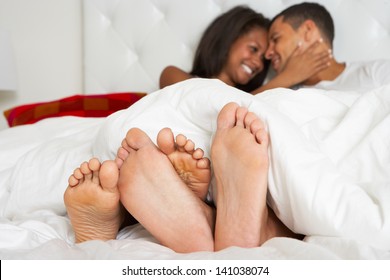 Couple Relaxing In Bed Wearing Pajamas