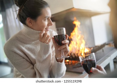  Couple Relaxing By The Fire Enjoying Glass Of Red Wine                              