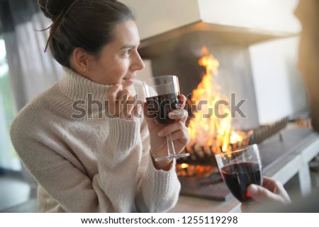  Couple relaxing by the fire enjoying glass of red wine                              