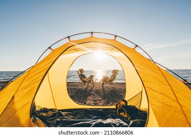 Couple Relaxing At Camping Tent Near The Sea At Sunset.