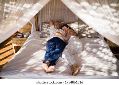 Couple relaxing in canopy bed during morning