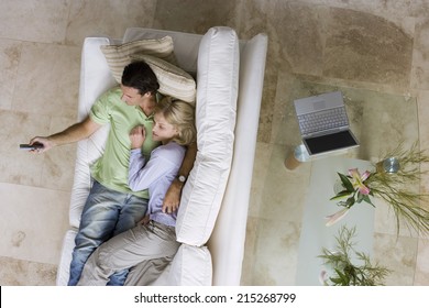 Couple Relaxing With Feet Up On Sofa At Home, Watching Tv, Man Holding Remote, Overhead View