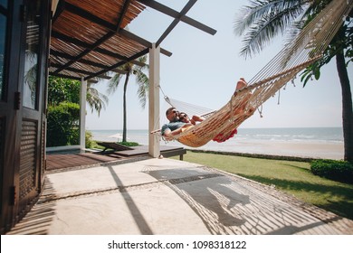 Couple relaxing in a hammock by the beach - Powered by Shutterstock