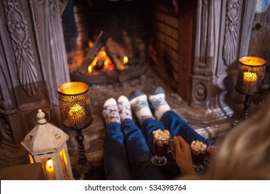 Couple Relaxing At Home. Feet In Wool Socks Near Fireplace. Winter Holiday Concept