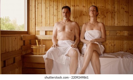 Couple Relaxing In Hot Sauna. Authentic, Real Sauna Moment.