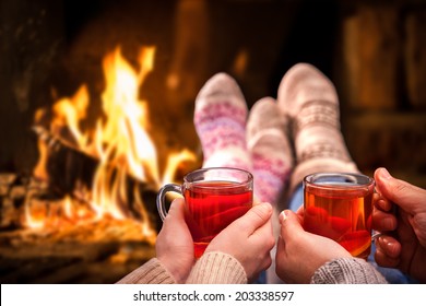 Couple relaxing with mulled wine at romantic fireplace on winter evening