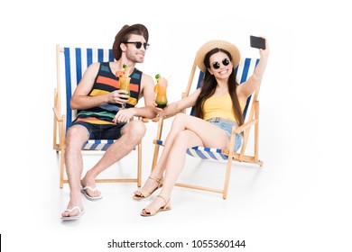 couple relaxing on beach chairs with cocktails and taking selfie, isolated on white - Powered by Shutterstock