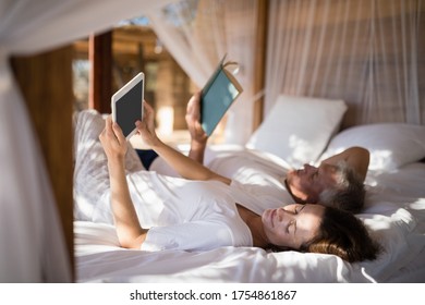 Couple relaxing on canopy bed during morning - Powered by Shutterstock