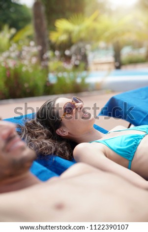 Couple relaxing on longchairs at resort pool