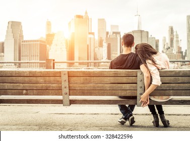 couple relaxing on New york bench in front of the skyline at sunset time. concept about love,relationship, and travel 