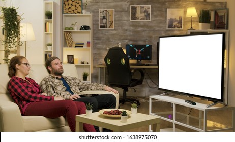 Couple Relaxing On Sofa Watching On Tv With Green Screen. Zoom In Shot.