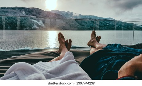 Couple relaxing on the sun beds in Spa, Badehaus Millstätter See, Austria, by Millstätter See. Only the legs are visible and some parts of bathrobes. Snowy mountains in the back, snow on the terrace - Shutterstock ID 1307744239