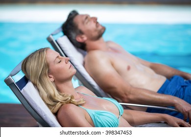 Couple Relaxing On A Sun Lounger Near Pool