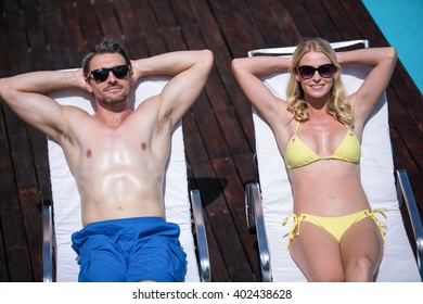 Couple Relaxing On A Sun Lounger Near The Pool