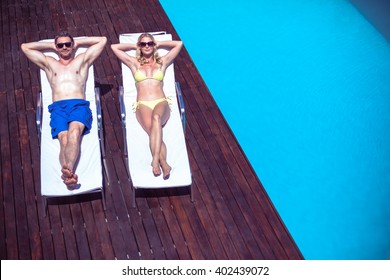 Couple Relaxing On A Sun Lounger Near The Pool