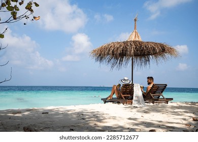 couple relaxing on tropical beach chairs - Powered by Shutterstock