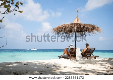 couple relaxing on tropical beach chairs
