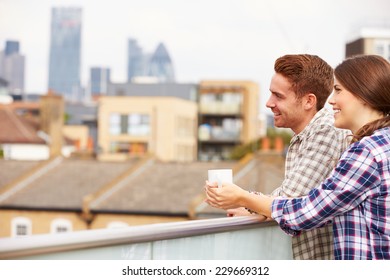 Couple Relaxing Outdoors On Rooftop Garden Drinking Coffee - Powered by Shutterstock