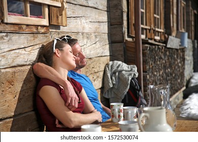 Couple Relaxing Outside Cabin At Ski Resort