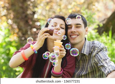 Couple Relaxing In The Park With Bubble Blower. Spring Time