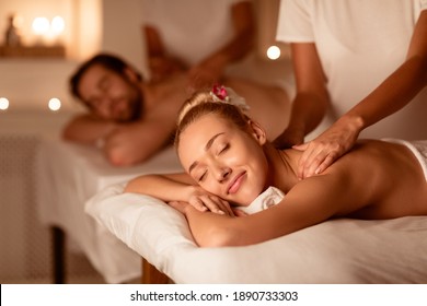 Couple Relaxing Receiving Back Massage Lying Closing Eyes At Romantic Luxury Spa With Burning Candles And Flowers. Wellness And Body Relaxation Therapy. Selective Focus, Low Light - Shutterstock ID 1890733303