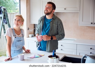 Couple Renovating Kitchen At Home Looking At Paint Swatches On Coffee Break - Powered by Shutterstock