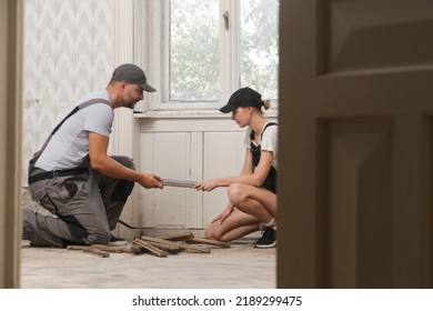 Couple Renovating Their Own Apartment. Home Improvement And DIY Project. Young Couple Is Removing Old Wooden Floor, Making Repairs To Their Home