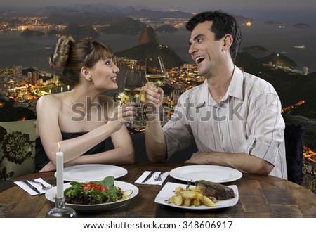 Couple in restaurant drinking wine with Rio de Janeiro in the background