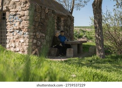 Couple resting at a rustic stone table next to a cottage in the countryside
