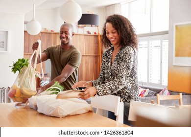 Couple Returning Home From Shopping Trip Unpacking Plastic Free Grocery Bags - Powered by Shutterstock
