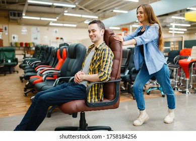 Couple Rides On Office Chair In Furniture Store