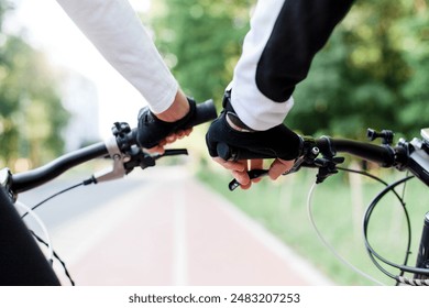 Couple riding bikes on bicycle path on road. Man and woman doing sport together. Healthy and sustainable lifestyle. Ecological outdoors activities. Close up of cyclist hands and handlebar, brakes - Powered by Shutterstock