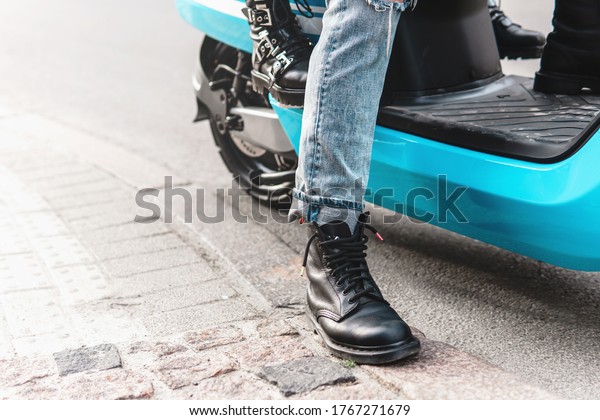 Couple riding motorcycle. Close-up of a scooter\
body and legs wearing\
boots